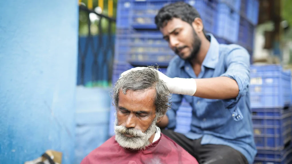 Volunteer giving a haircut to a homeless person as part of the Transformers Rehabilitation Program.webp